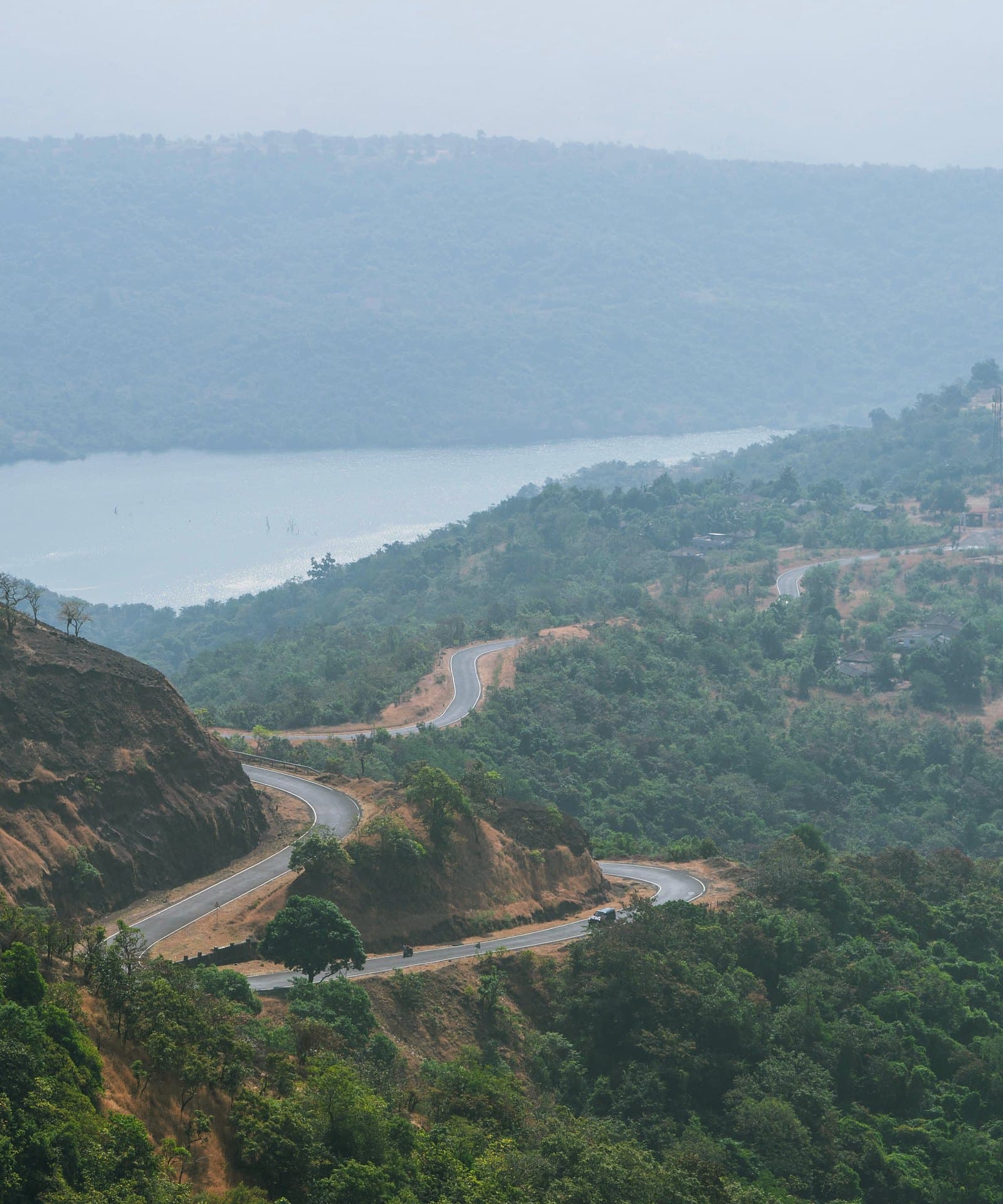 A road winding down through the Konkan ghats towards a river